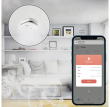 Scenă dintr-o sufragerie cu detector de fum pe tavan și un smartphone care afișează o aplicație de detector de fum cu o notificare