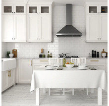 Bucătărie luminoasă cu dulapuri albe, hotă de aragaz și masă aranjată