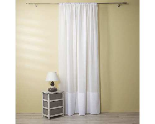 Scenă cu o perdea albă atârnând de o bară de perdea și o noptieră cu o lampă