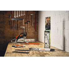 Scenă cu un ferăstrău cu lanț, un kit de tăiere STIHL, ochelari de protecție și mănuși pe o masă de lemn