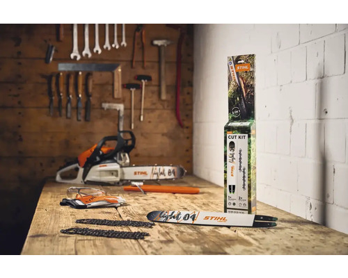 Scenă cu un ferăstrău cu lanț, un kit de tăiere STIHL, ochelari de protecție și mănuși pe o masă de lemn