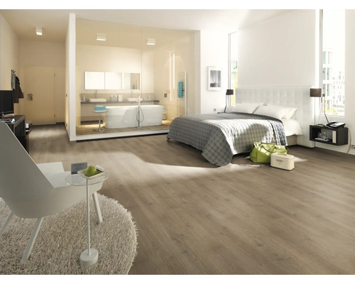 Dormitor luminos cu zonă de baie, podea laminată, pat și cadă