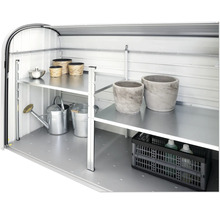 Vedere interioară a unei magazii de grădină cu rafturi și accesorii de grădină, cum ar fi stropitoare și jardiniere.