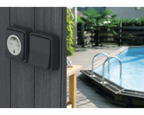 Priză de exterior și întrerupător pe un perete de lemn lângă o piscină