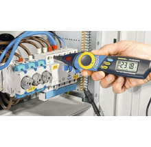 O mână ține un stilou multimetru digital de un distribuitor de circuit electric