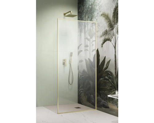 Duș Walk In Radaway Modo F SL Brushed Gold, 90x200 cm, sticlă transparentă, profil auriu, stânga Cabină de duș cu duș fix și duș de mână în fața unui perete cu motiv de junglă.