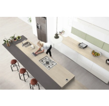 Bucătărie modernă cu insulă de gătit, chiuvetă, scaune de bar și femeie cu laptop