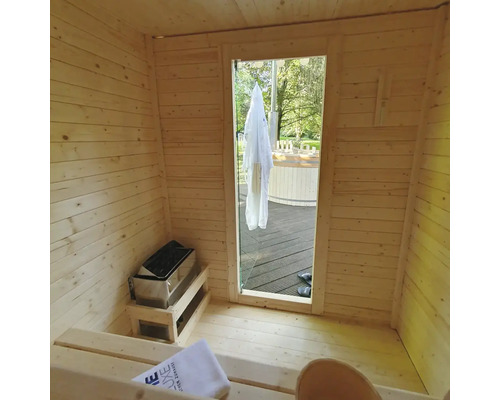 Vedere interioară a unei saune cu panouri din lemn, sobă de saună și vedere spre exterior
