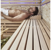 Bărbat relaxându-se într-o saună cu bănci din lemn și accesorii.
