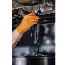 Mână cu mănușă de protecție schimbând uleiul de motor