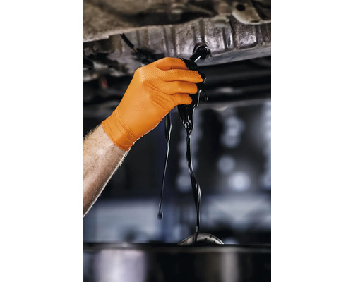 Mână cu mănușă de protecție schimbând uleiul de motor
