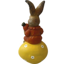 Iepure decorativ pe un ou de Paște cu un morcov în mână ca decorație de grădină