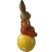 Figurină de iepuraș de Paște șezând pe un ou galben ca decorațiune