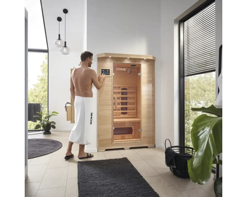 Bărbat care operează o saună cu infraroșu Home Deluxe într-o baie