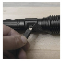 O mână conectează un cablu USB la o lanternă LED.