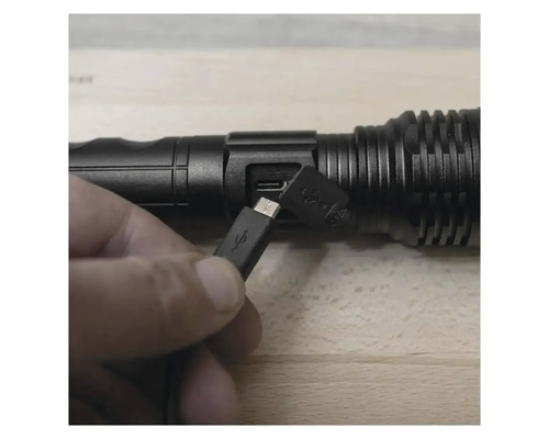 O mână conectează un cablu USB la o lanternă LED.