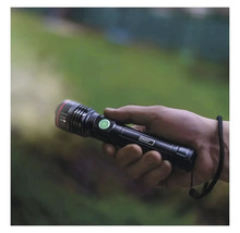 O mână ține o lanternă Emos neagră care luminează.