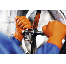 Mâini cu mănuși de protecție care operează o supapă metalică