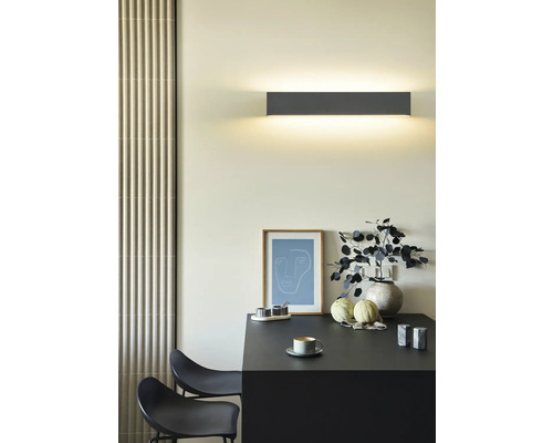 Lumină de perete deasupra unei mese cu decorațiuni într-o cameră luminoasă.