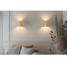 Două lămpi de perete aurii iluminează o zonă de living cu canapea și decorațiuni.