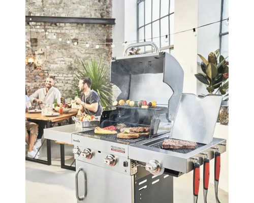 Scenă cu grătar pe gaz din oțel inoxidabil cu mâncare și persoane în fundal