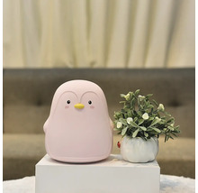 Lampă decorativă pinguin lângă o plantă în ghiveci