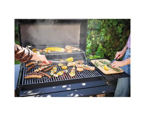 Persoane care fac grătar cârnați, legume și carne pe un grătar cu cărbune cu masă laterală