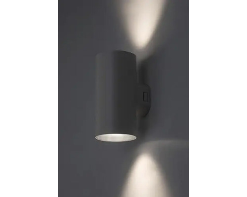 Lampa de perete cilindrică din metal iluminează un perete