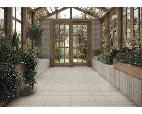 Imagine de interior a unei grădini de iarnă cu plante, podea cu gresie și elemente din lemn.