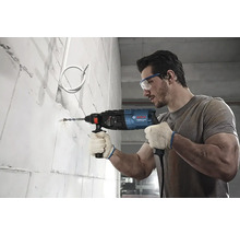 Un bărbat găurește un perete cu o mașină de găurit cu percuție.