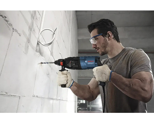 Un bărbat găurește un perete cu o mașină de găurit cu percuție.
