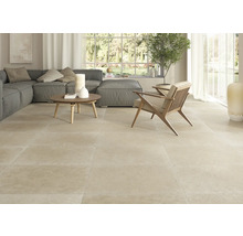 Cameră de zi luminoasă cu gresie, canapea și fotoliu.