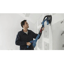 Un bărbat folosește o șlefuitoare cu gât lung pentru a șlefui un perete.