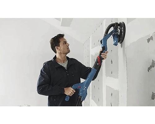 Un bărbat folosește o șlefuitoare cu gât lung pentru a șlefui un perete.