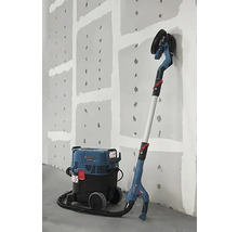 Șlefuitor de perete cu aspirator în fața unui perete