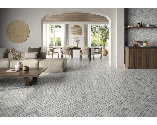 Living luminos cu podea cu gresie în model herringbone, canapea, masă de sufragerie și decorațiuni.