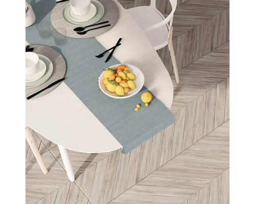 Masa cu veselă, bol cu fructe și față de masă pe o podea de lemn