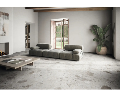 Living luminos cu canapea modulară, măsuță de cafea, plantă de interior și podea cu gresie.