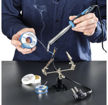 O persoană sudează cabluri cu un pistol de lipit, cositor de lipit și flux de lipit pe o suprafață de lucru.