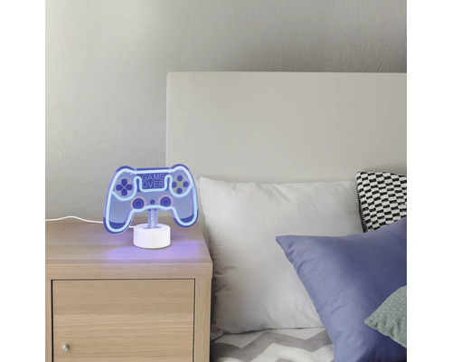 Lampă decorativă Game Over în formă de controller de joc pe o noptieră în dormitor.