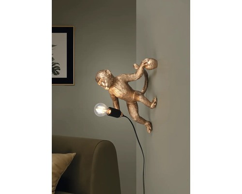 Lampă de perete aurie cu maimuță și bec pe un perete