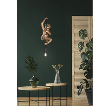 Lampă suspendată decorativă în formă de maimuță într-un interior cu plante și măsuțe laterale