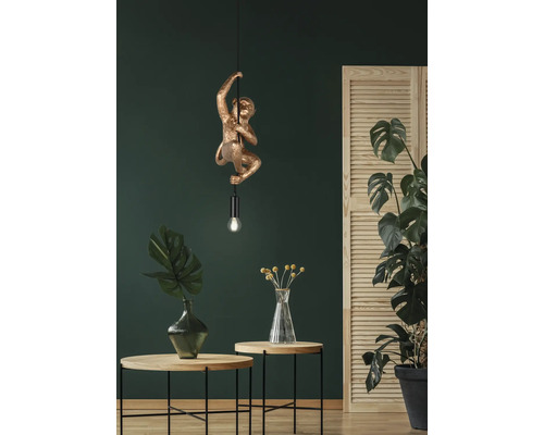 Lampă suspendată decorativă în formă de maimuță într-un interior cu plante și măsuțe laterale