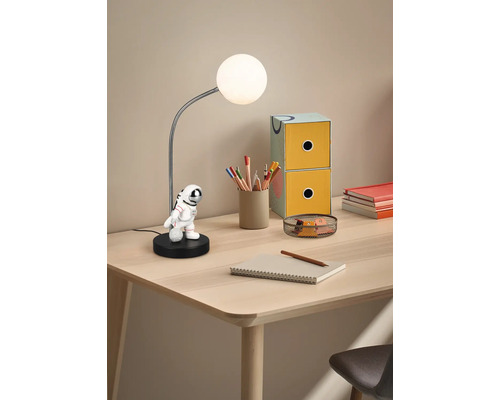 Lampă de masă cu figurină astronaut pe un birou