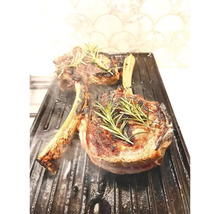 Două fripturi T-bone la grătar cu rozmarin pe o placă de grătar