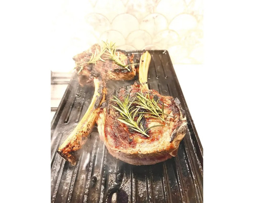 Două fripturi T-bone la grătar cu rozmarin pe o placă de grătar