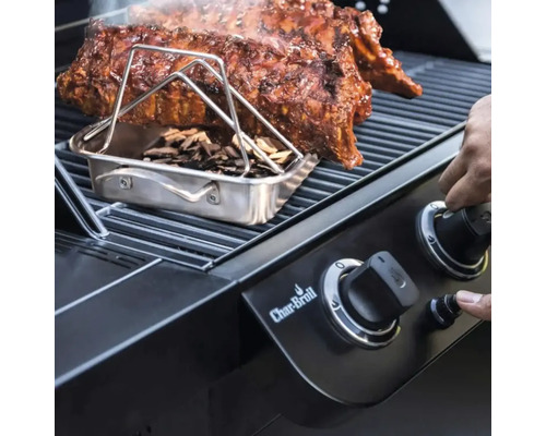 Grătar cu coaste, cutie de afumare și așchii de lemn și o mână pe un buton rotativ