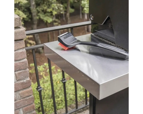 Perie de grătar pe o masă laterală a unui grătar