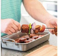 Bărbat înșirând carne și legume pe o frigăruie deasupra unui vas cu bucăți de carne