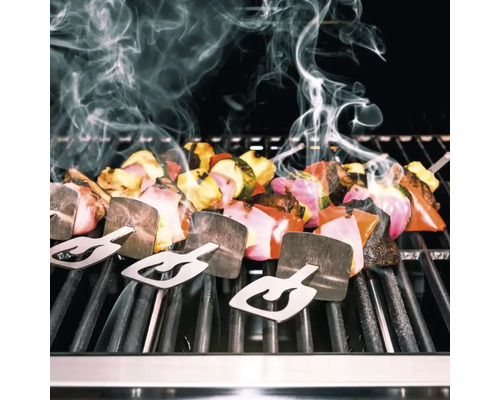 Frigărui de legume cu suporturi pe un grătar cu degajare de fum